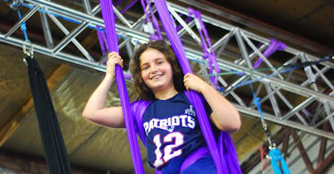 young girl smiling on an aerial fabric