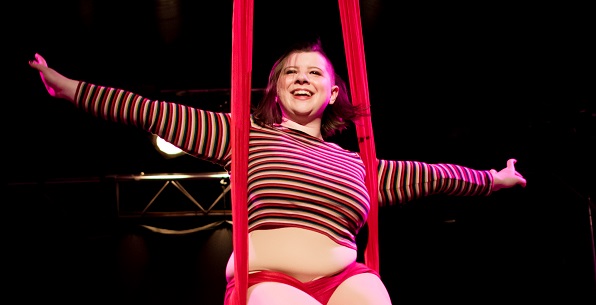 smiling woman in sitting position on aerial silks